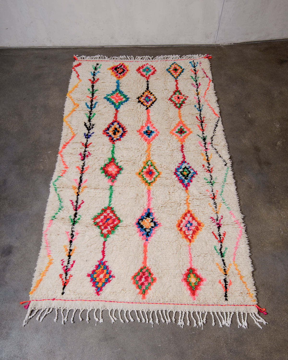 Berberlin Azilal rug made of fluffy wool and cotton, laying flat on a concrete floor.